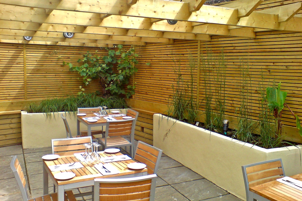 Refurbished restaurant garden with rendered raised beds, timber wall screening, pergola and garden lighting.